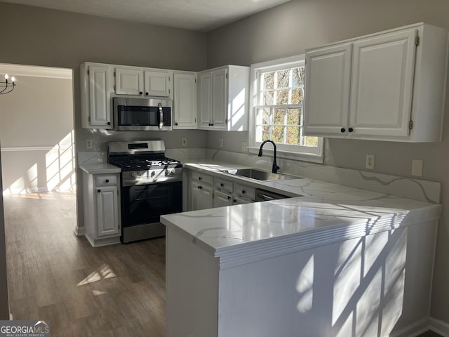 kitchen with white cabinets, sink, appliances with stainless steel finishes, dark hardwood / wood-style flooring, and kitchen peninsula