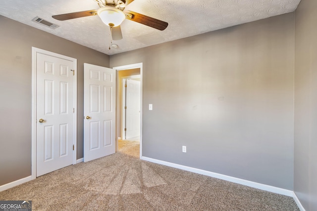 unfurnished bedroom featuring carpet, a textured ceiling, and ceiling fan