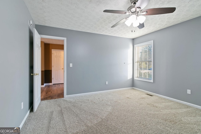 carpeted spare room with ceiling fan and a textured ceiling