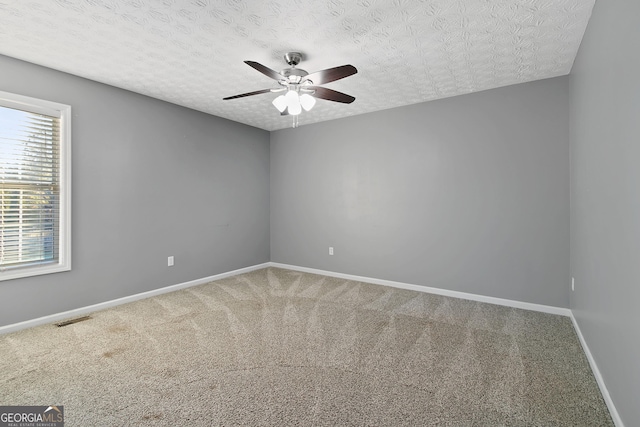 carpeted spare room featuring ceiling fan and a textured ceiling