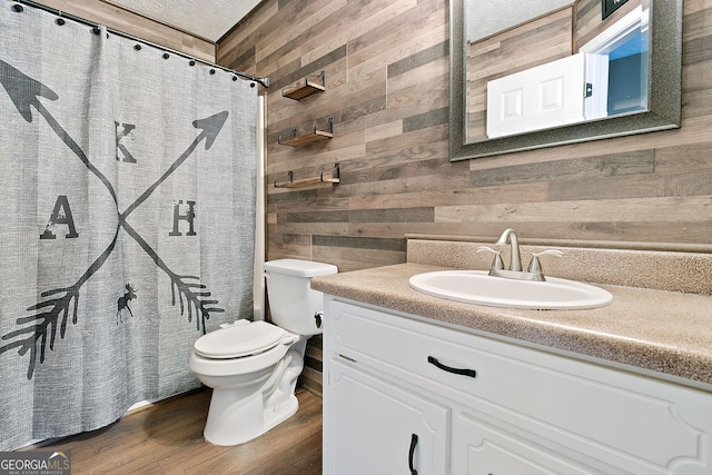 bathroom with walk in shower, wood walls, hardwood / wood-style floors, toilet, and vanity