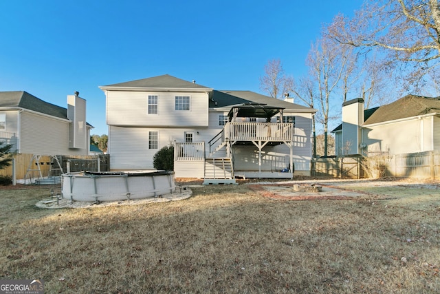 rear view of property featuring a swimming pool side deck and a lawn