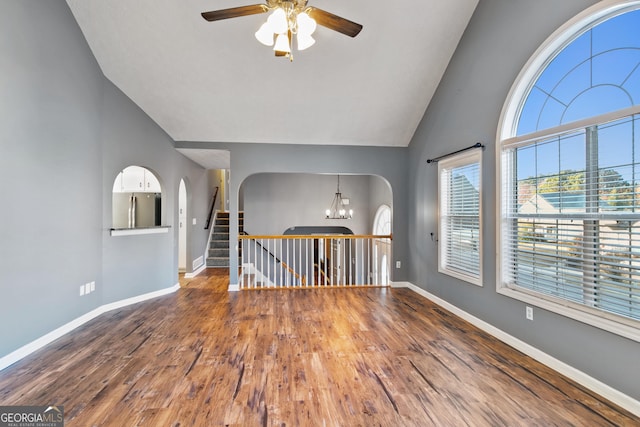 unfurnished room with vaulted ceiling, wood-type flooring, and ceiling fan with notable chandelier