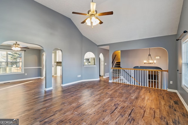 unfurnished living room with ceiling fan with notable chandelier, hardwood / wood-style flooring, and high vaulted ceiling