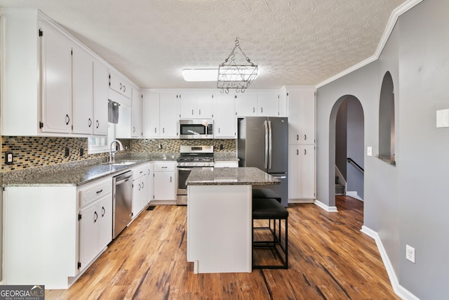 kitchen with white cabinets, a center island, light wood-type flooring, and stainless steel appliances