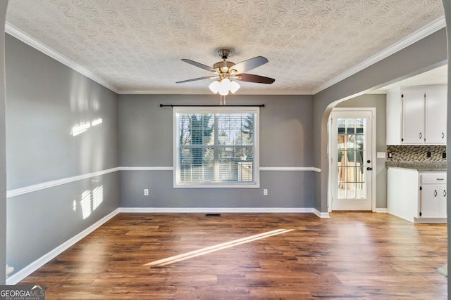 unfurnished dining area featuring wood-type flooring, a textured ceiling, ceiling fan, and ornamental molding