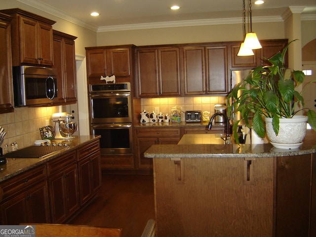 kitchen featuring dark wood-type flooring, stainless steel appliances, pendant lighting, a breakfast bar area, and ornamental molding