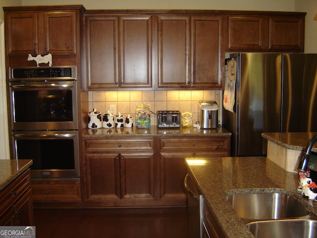 kitchen featuring appliances with stainless steel finishes, stone countertops, tasteful backsplash, and sink