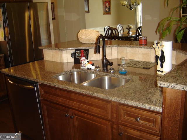 kitchen with stainless steel appliances, light stone counters, and sink