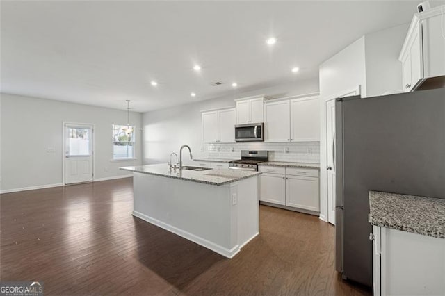 kitchen with a center island with sink, sink, light stone countertops, appliances with stainless steel finishes, and dark hardwood / wood-style flooring