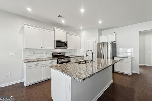 kitchen with white cabinetry, sink, stainless steel appliances, dark hardwood / wood-style flooring, and a center island with sink