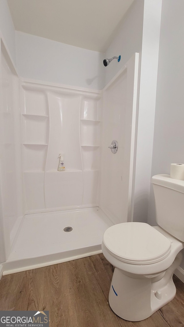 bathroom with a shower, wood-type flooring, and toilet