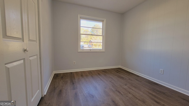 empty room featuring wooden walls and dark hardwood / wood-style floors