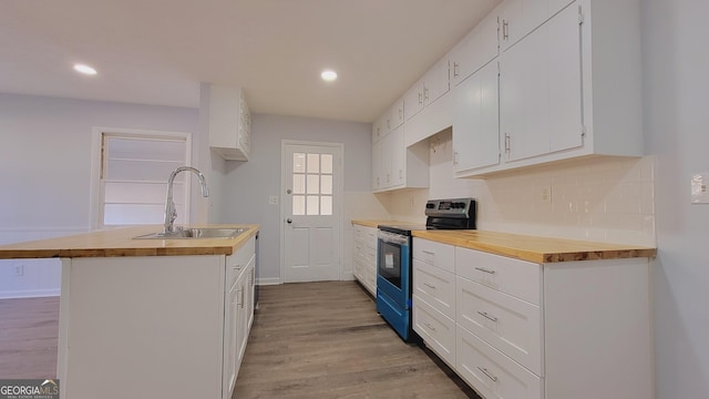 kitchen featuring sink, stainless steel range with electric cooktop, a center island with sink, white cabinets, and light wood-type flooring