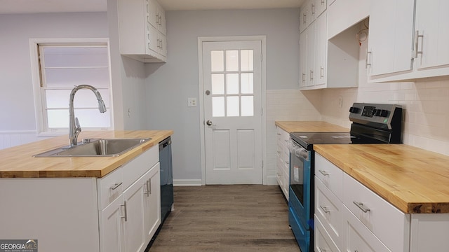 kitchen with stainless steel electric stove, butcher block countertops, white cabinets, and sink