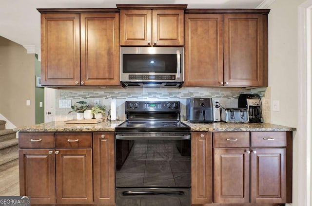 kitchen with stainless steel microwave, light stone countertops, decorative backsplash, brown cabinetry, and black electric range oven