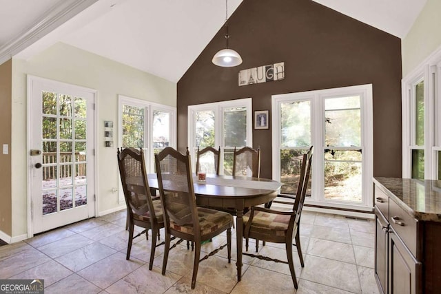 dining space with baseboards and high vaulted ceiling