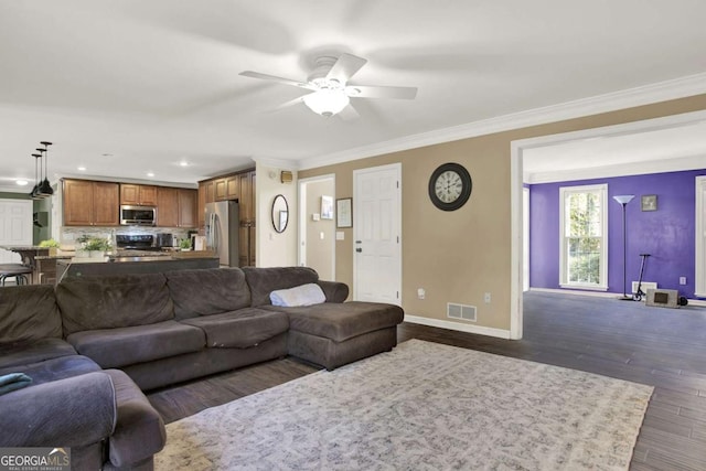 living room with visible vents, crown molding, baseboards, dark wood-style floors, and a ceiling fan