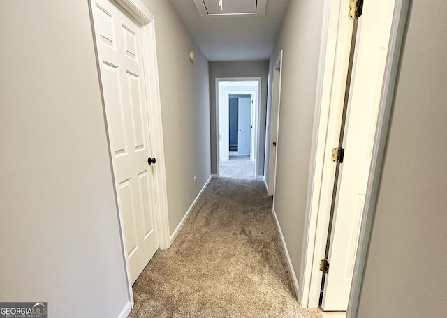 corridor featuring baseboards and light carpet