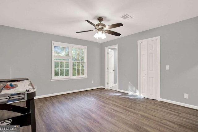 interior space featuring visible vents, ceiling fan, baseboards, wood finished floors, and a closet