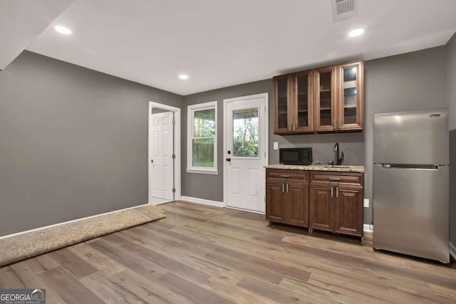 kitchen featuring baseboards, visible vents, freestanding refrigerator, light wood-style floors, and black microwave