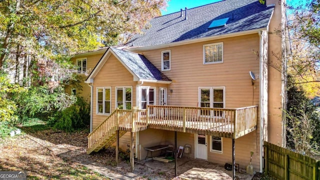 rear view of house featuring fence, roof with shingles, a wooden deck, a chimney, and stairs