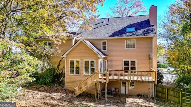 back of property with stairs, fence, a shingled roof, a wooden deck, and a chimney