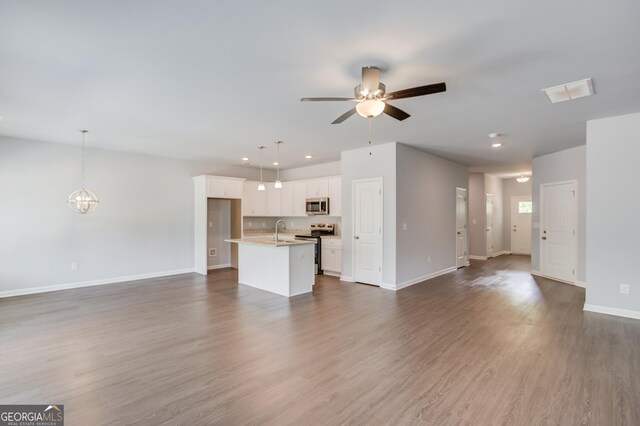 unfurnished living room featuring ceiling fan with notable chandelier, sink, and dark wood-type flooring