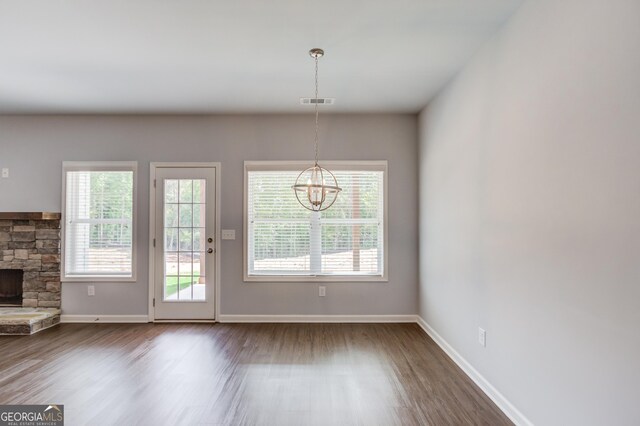 entryway with a stone fireplace, hardwood / wood-style floors, and a notable chandelier