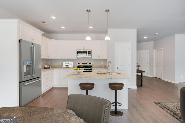 kitchen with white cabinetry, sink, pendant lighting, appliances with stainless steel finishes, and light wood-type flooring