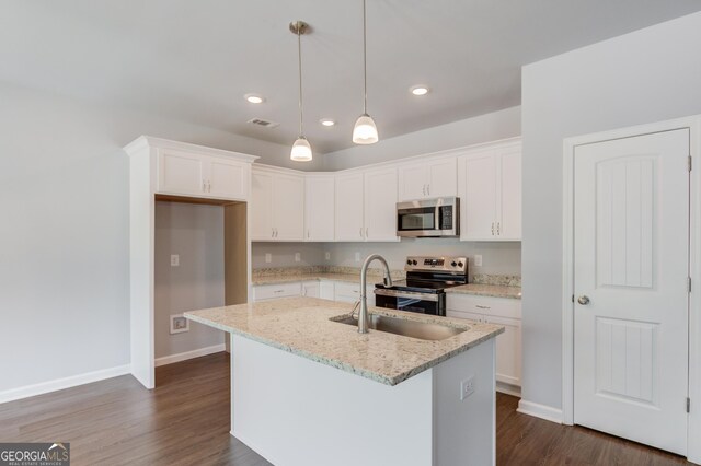 kitchen with a kitchen island with sink, dark wood-type flooring, white cabinets, appliances with stainless steel finishes, and light stone counters