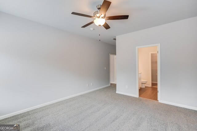 unfurnished bedroom with ceiling fan, light colored carpet, and ensuite bathroom