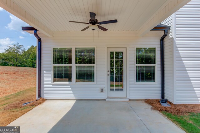 view of exterior entry with a patio area and ceiling fan