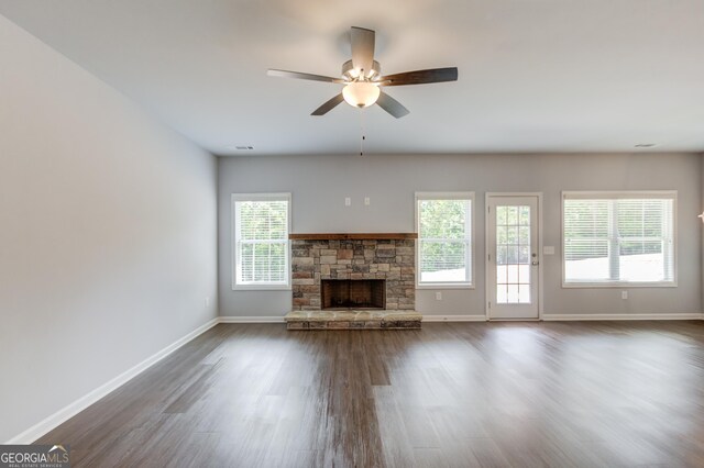 unfurnished living room featuring a stone fireplace, ceiling fan, and dark wood-type flooring