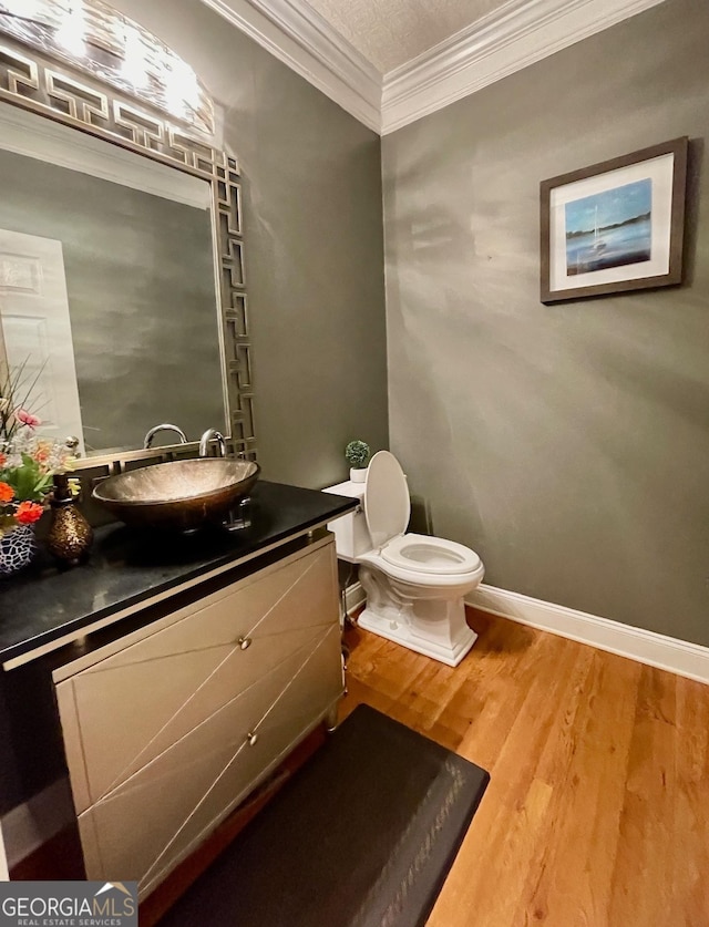 bathroom featuring vanity, toilet, wood-type flooring, and crown molding