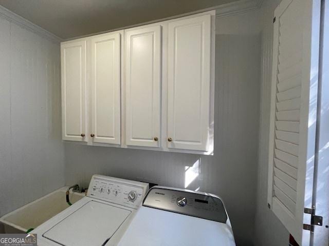 clothes washing area with cabinets, crown molding, and washing machine and clothes dryer