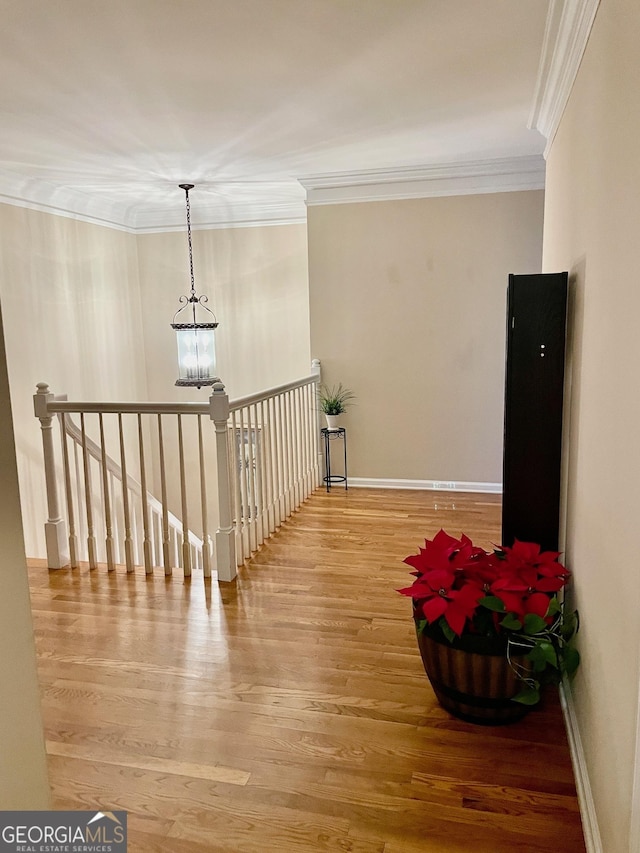 hall with hardwood / wood-style floors, crown molding, and an inviting chandelier