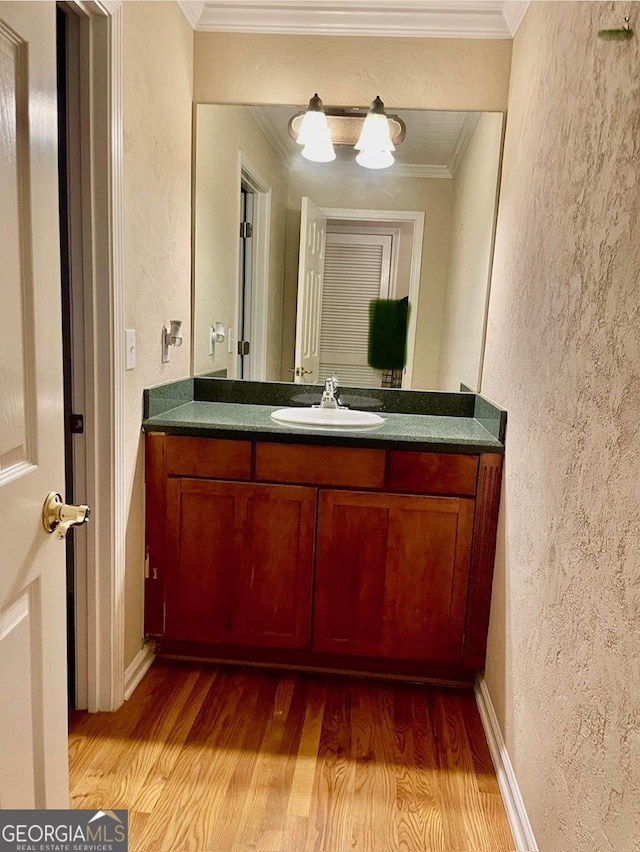 bathroom featuring hardwood / wood-style floors, vanity, and crown molding