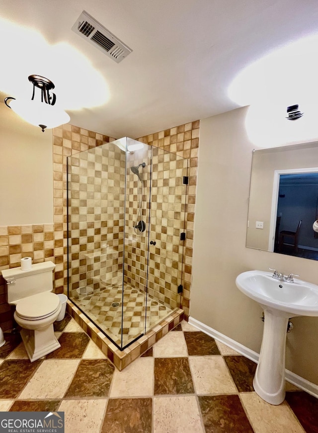 bathroom featuring a shower with shower door and toilet