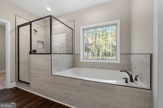 bathroom with independent shower and bath and wood-type flooring