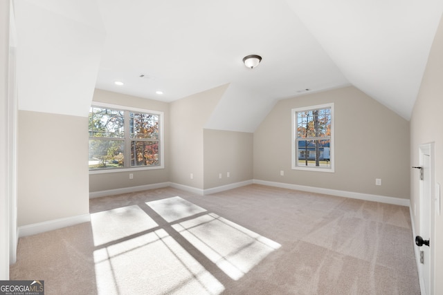 bonus room featuring plenty of natural light, light colored carpet, and vaulted ceiling