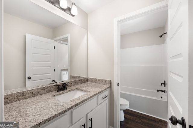 full bathroom featuring washtub / shower combination, wood-type flooring, vanity, and toilet