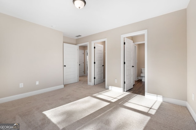 unfurnished bedroom featuring connected bathroom and carpet floors