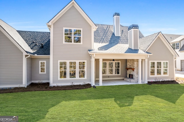 rear view of house featuring a fireplace, a ceiling fan, a yard, a chimney, and a patio area