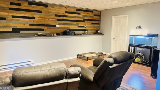 living room with wood walls, light hardwood / wood-style floors, and baseboard heating