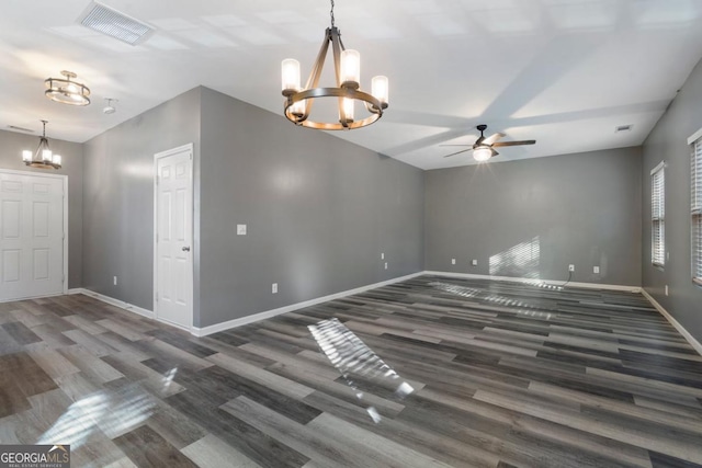 unfurnished room featuring ceiling fan with notable chandelier, dark wood-style flooring, visible vents, and baseboards