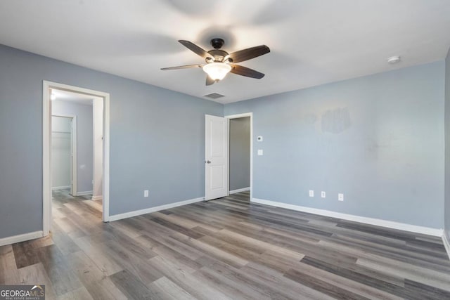 unfurnished bedroom featuring ceiling fan, wood finished floors, visible vents, and baseboards