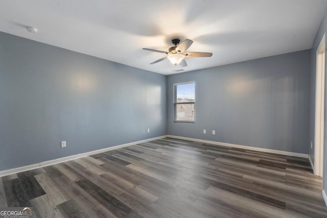 empty room featuring dark wood-style floors, visible vents, a ceiling fan, and baseboards