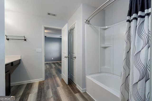 bathroom featuring visible vents, shower / bath combo, vanity, wood finished floors, and baseboards