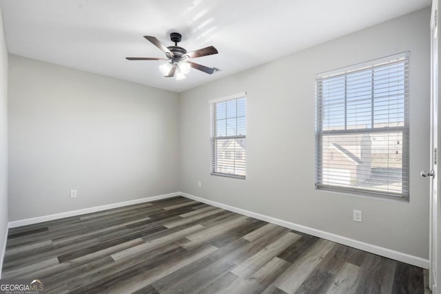 unfurnished room featuring dark wood-style flooring, ceiling fan, and baseboards